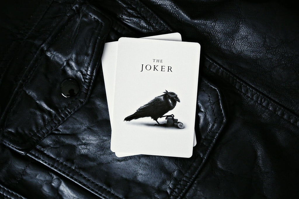 Madison Rounders White Playing Cards — Joker card design by Daniel Madison on black leather surface