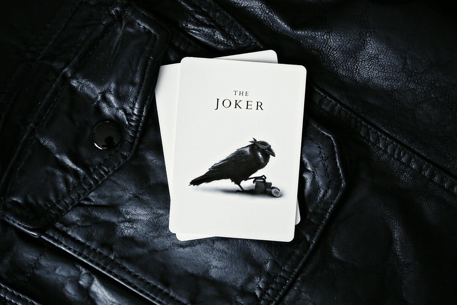 Madison Rounders White Playing Cards — Joker card design by Daniel Madison on black leather surface